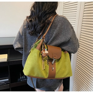 Detail of olive green suede tote bag showing brown leather straps and cute bear charm pendant