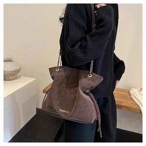 Macro view of dark brown matte leather tote with chain strap and fashion lettering detail
