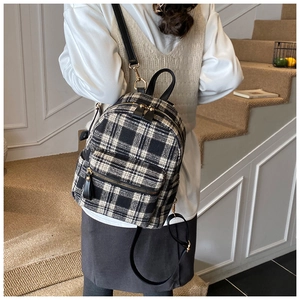 Detail of classic black and white plaid mini backpack worn by model on stairs