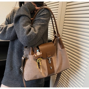 Detail of suede and leather tote bag with bear charm and adjustable strap