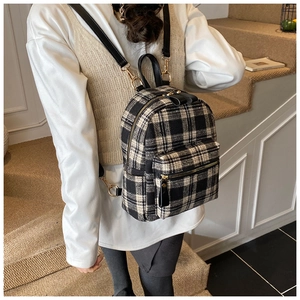 Detail of checkered tweed backpack featuring gold hardware and black leather straps