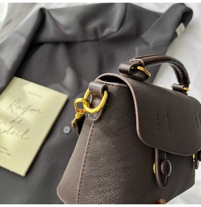 Macro detail of dark brown lychee textured leather bag with vintage gold metal hardware