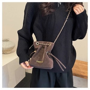 Detail of matte dark brown bucket bag with gold chain strap and drawstring closure