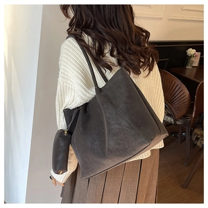 Detail view of large brown tote bag with matching inner pouch on casual outfit