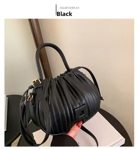 Détail de la texture plissée noire du sac à main avec fermoir doré et bandoulière