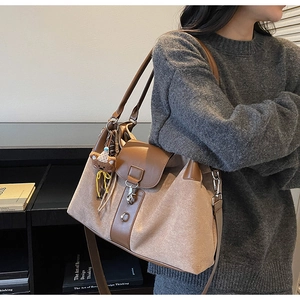 Detail of suede canvas tote bag with brown leather trim and cute knit bear charm