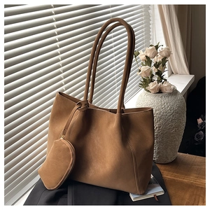 Close-up of matte brown tote bag with hanging coin purse in warm sunlight setting