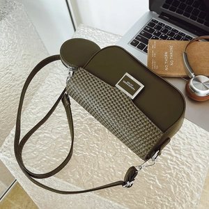 Detailed shot of an olive green crossbody bag with woven texture on an office desk