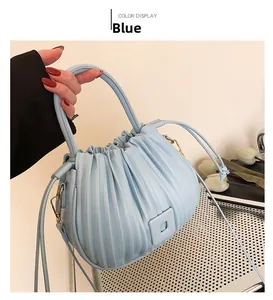 Détail du sac seau plissé bleu clair montrant le cordon de serrage et boucles dorées