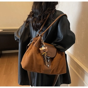 Brown frosted leather tote bag detail with decorative buckle and cute bear pendant