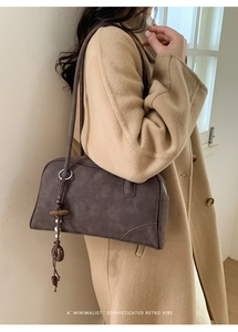 Detail of dark brown faux suede shoulder bag with wood bead tassel on a model