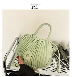 Détail du sac à main vert clair plissé avec poignée ronde et finitions dorées en décor réel