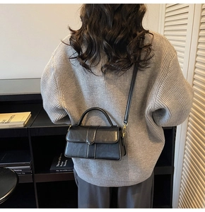 Détail d'un sac bandoulière vintage en cuir noir porté par un mannequin en studio