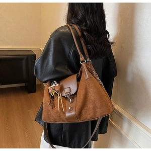 Detailed back view of brown leather tote bag with suede trim and cute bear charm