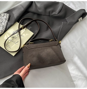 Detail view of dark brown textured crossbody bag with retro gold hardware and shoulder strap