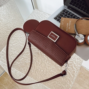 Detail of burgundy crossbody bag with lychee leather and coin purse on desk