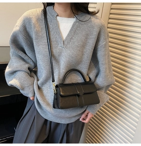 Detail of minimalist black leather square handbag with top handle and shoulder strap