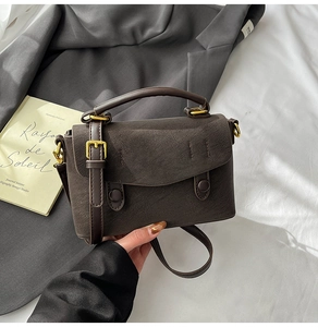Detail of dark brown vintage crossbody bag with flap and retro hardware on fabric