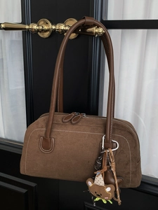 Retro brown suede Boston shoulder bag with cute bear charm hanging on a door handle