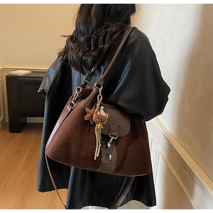 Detail of dark brown tote bag featuring suede texture, metal buckle and cute bear pendant