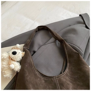Detail of coffee brown hobo bag with contrast stitching and plush bear charm