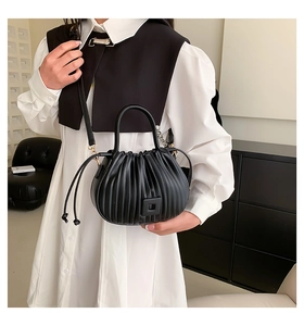Détail d'un sac bandoulière noir plissé avec texture en similicuir et boucle magnétique