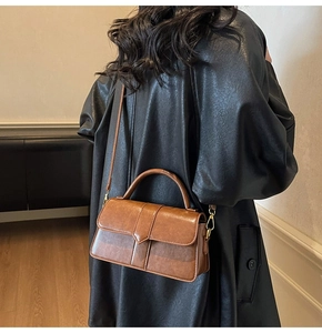 Gros plan d'un sac à main vintage en cuir marron avec détails dorés et poignée chic