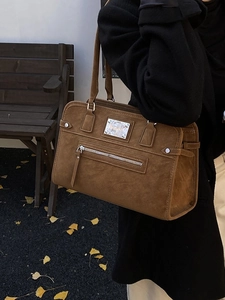Sac cabas vintage en cuir mat marron foncé porté par un mannequin dans un parc d'automne