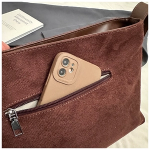Gros plan d'un sac cabas en daim marron avec une poche zippée contenant un smartphone