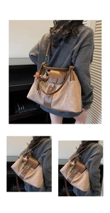 Detail of beige tote bag showing brown leather handles and a cute bear keychain charm