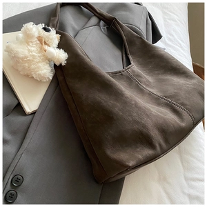 Detail of dark brown faux suede tote bag with contrast stitching and plush bear charm