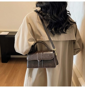Détail du sac en cuir vintage marron foncé montrant les ferrures dorées et la bandoulière