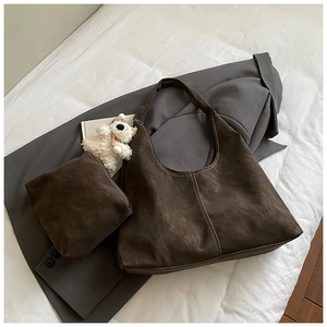 Close-up of deep brown suede handbag set with contrasting white decorative stitching