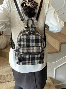 Classic black and white checkered tweed backpack with gold zippers shown on a model