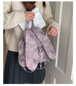 Detail of vintage star-patterned mini rabbit ear backpack held by a model in sweater