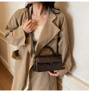 Sac à main en cuir marron foncé mat porté avec un trench kaki pour un look d'hiver chic