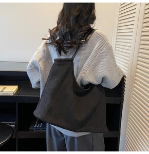 Detail of large black suede tote bag showing soft texture and shoulder strap fit