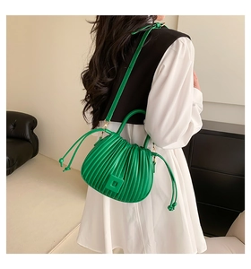 Détail du sac plissé vert avec cordons de serrage et décoration en relief carrée