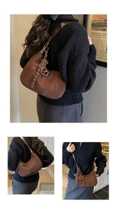 Borsa a mezzaluna in camoscio marrone con tracolla in pelle e ciondolo a forma di pretzel