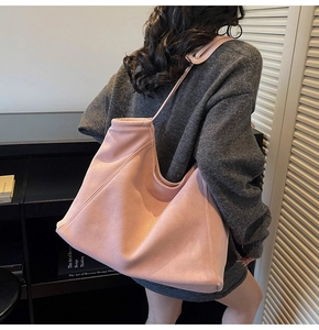 Pink matte tote bag detail with wide strap and decorative stitching on suede material
