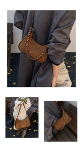 Detalle de bolso medialuna de ante marrón con cadena dorada y estilo otoñal chic