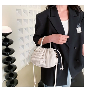 Détail du sac à main plissé beige avec boucle carrée et bandoulière amovible élégante