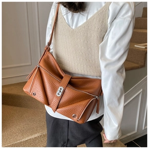 Detail of a brown lychee pattern leather shoulder bag with geometric folding and silver lock