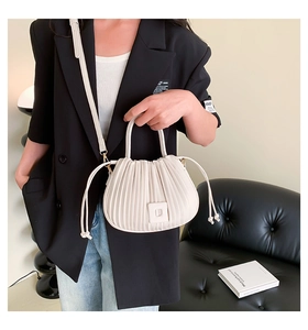Détails du sac plissé crème montrant les plis verticaux et la bandoulière amovible