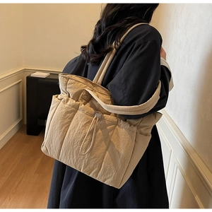 Quilted tote bag detail showing khaki fabric texture and front drawstring pocket