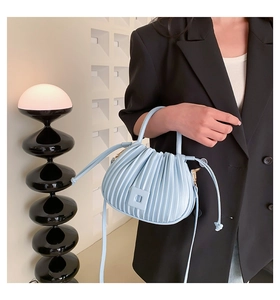 Détail du sac à main plissé bleu clair avec texture verticale et finitions dorées