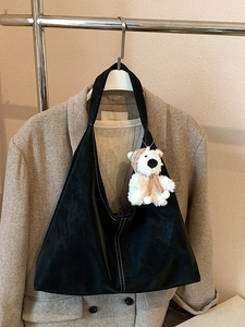 Minimalist black hobo shoulder bag with white contrast stitching and a teddy bear charm