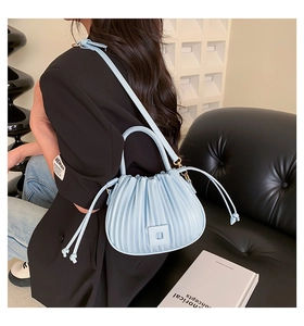 Détail d'un sac à main en cuir plissé bleu clair avec des plis accordéon verticaux