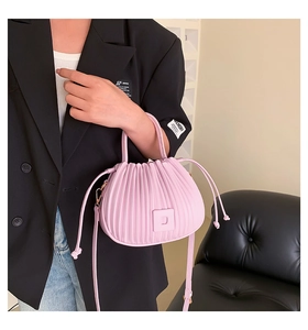 Sac à main rose plissé avec cordon et logo D porté par un mannequin en blazer noir