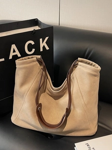 Large khaki suede hobo tote bag with dark brown leather straps on a black sofa